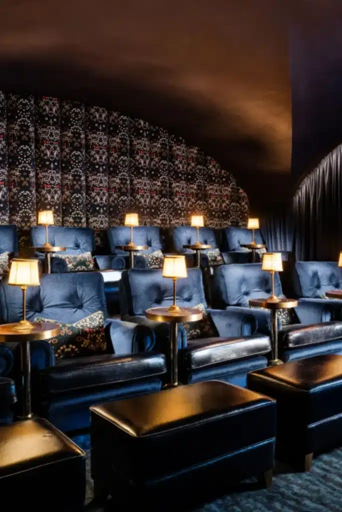 Private cinema experience at Mount Juliet Estate, County Kilkenny, Ireland — deep blue velvet seating with patterned cushions, each paired with a small side table and individual table lamp.