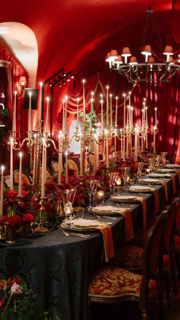 Luxurious red banquet hall with a long candlelit table, gold candlesticks, and crimson drapes.