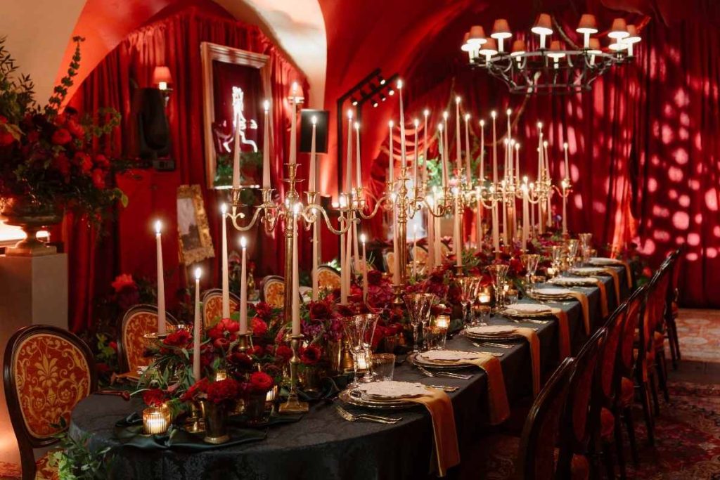 Private celebration at Ashford Castle — candlelit dining experience in the castle dungeon with rich red décor, layered tablescape design and atmospheric lighting.